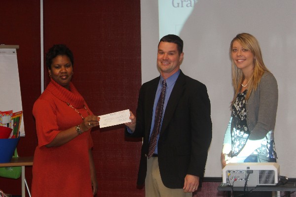 Patrice Brown (l), principal of Edgewood Middle School, receives a science, technology, engineering and mathematics check for $3,500 in January from chapter representatives Stacy Kauffman, 5K planning committee chair, and Tim Jahnigan, vice president of Young AFCEANs.